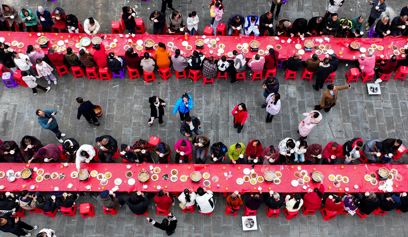2025年12月21日，貴州省銅仁市玉屏侗族自治縣新店鎮大灣村，游客和村民在品嘗長桌宴。