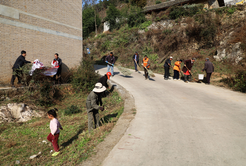 保潔員、護林員與村民代表正在打掃村主干道。