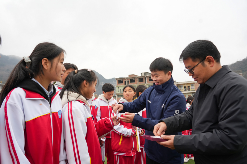 2025年12月24日,貴州省畢節市納雍縣化作中學,納雍籍奧運冠軍謝瑜在給同學們派發“小謝瑜”勛章。