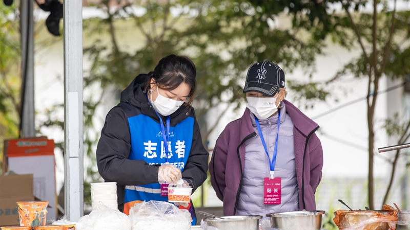志愿者在補給點為選手準備美食。