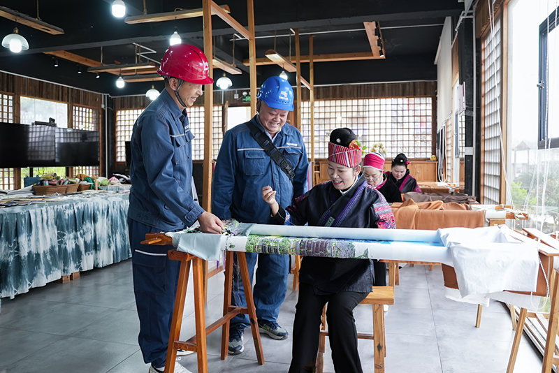 凱里施秉供電局供電員在與公司繡娘了解用電情況。