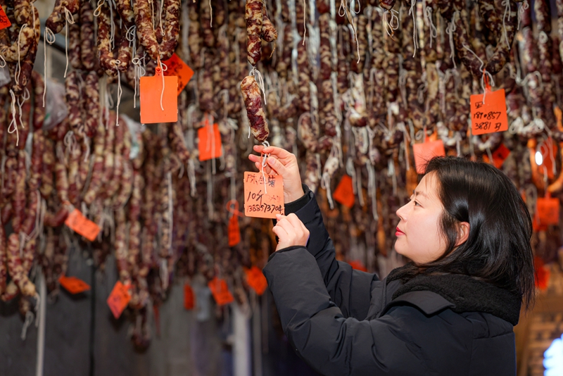 2026年1月26日，貴州省畢節市七星關區鋤禾農特產品店工人給顧客定制的香腸懸掛標簽。