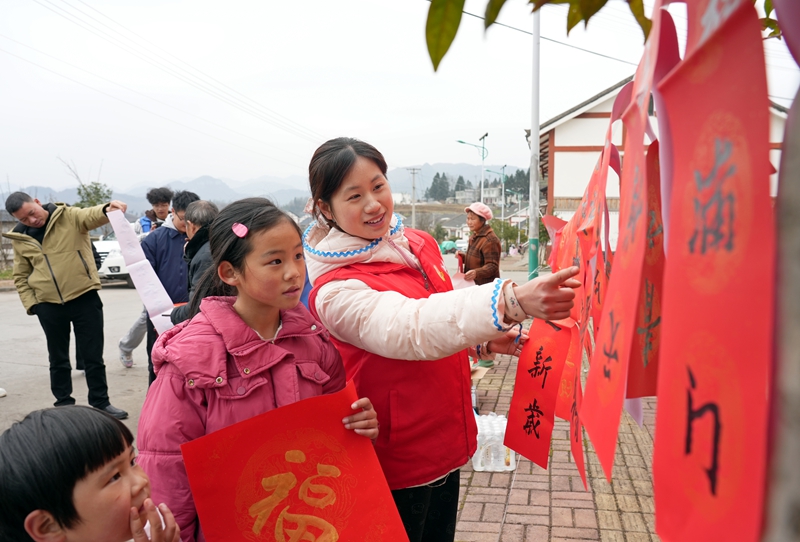 2026年1月26日，貴州省畢節(jié)市納雍縣張家灣鎮(zhèn)普灑社區(qū)，大學(xué)生志愿者和小朋友一起挑選春聯(lián)。