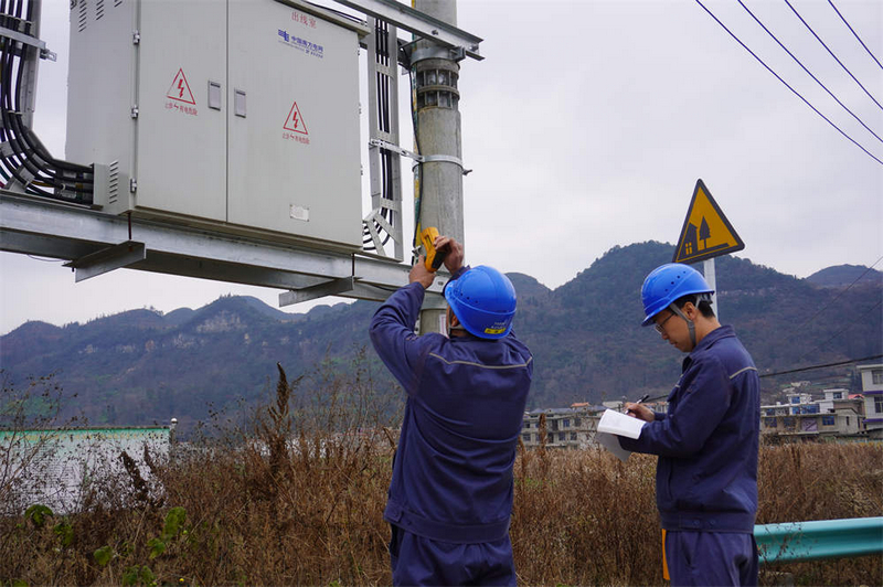 工作人員正對村寨中的配變進行巡視測溫。