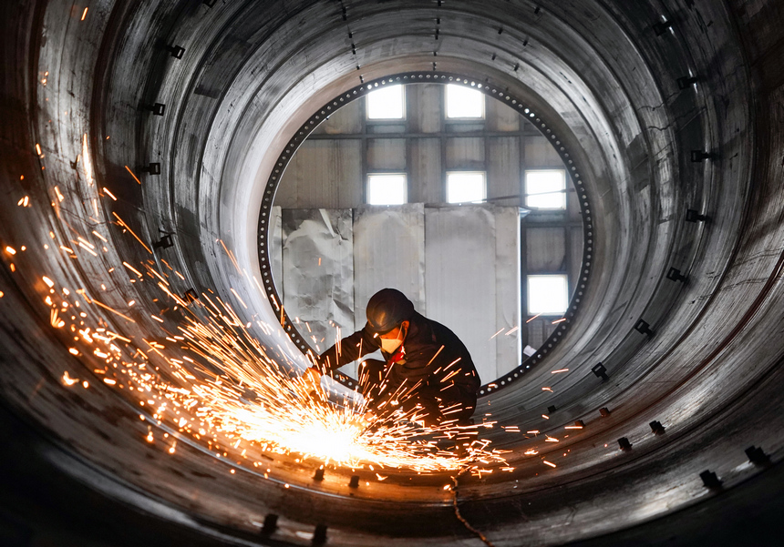 在位于貴州威寧經濟開發區的貴州保龍設備制造有限公司風電塔筒生產車間,工人在對焊接好的塔筒進行焊接口打磨。趙慶能攝