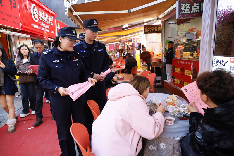 工作人員在會展中心附近檢查小吃攤點食品安全并向顧客發放宣傳資料。