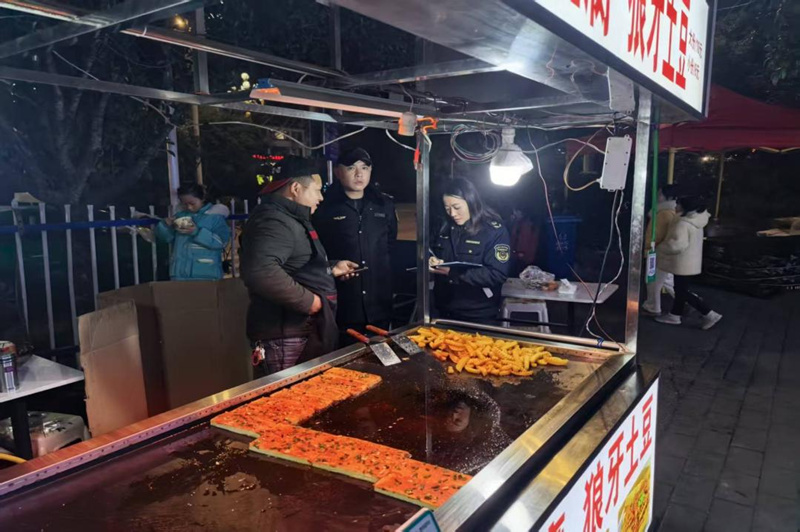 施秉縣市場監管局執法人員在檢查小吃攤食品安全。