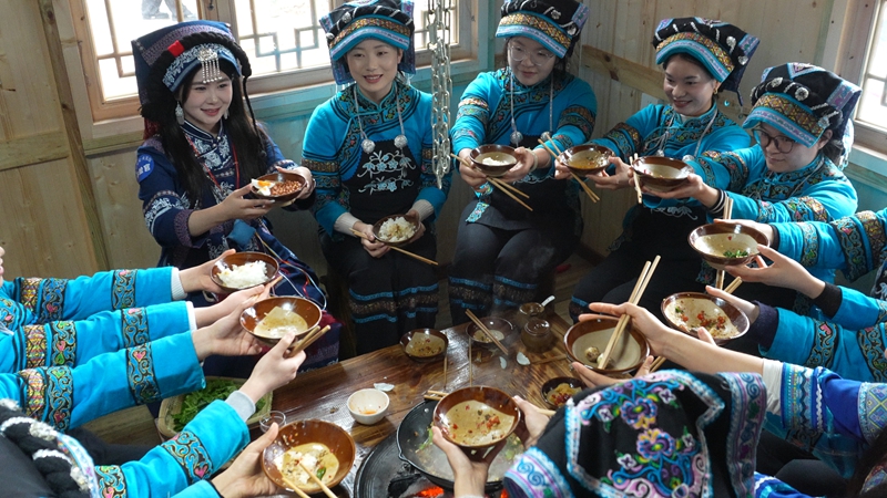 少數民族少女共品美食。