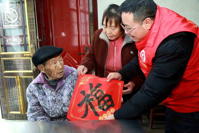 書(shū)法志愿者在貴州省遵義市播州區(qū)龍坑街道八里社區(qū)為102歲淳祖開(kāi)老人送上書(shū)寫(xiě)的“福”。