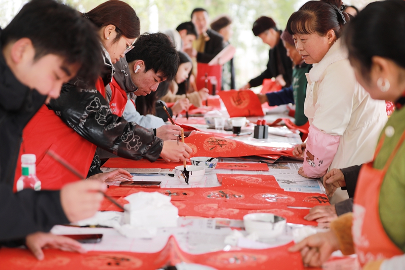 貴州省黔西市林泉鎮營腳村村民在參加新春大聯歡活動，大學生志愿者在給村民寫春聯。
