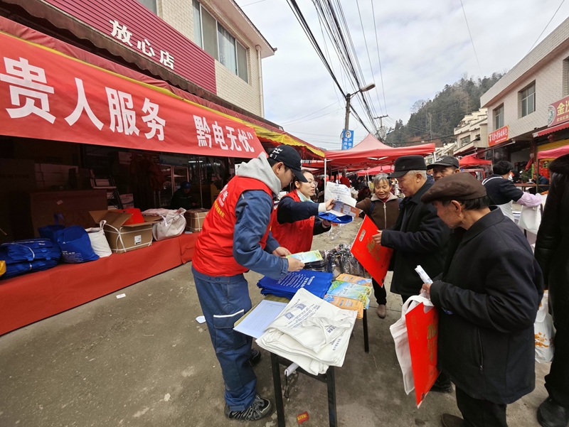 志愿者向趕集群眾發展安全用電宣傳用品。