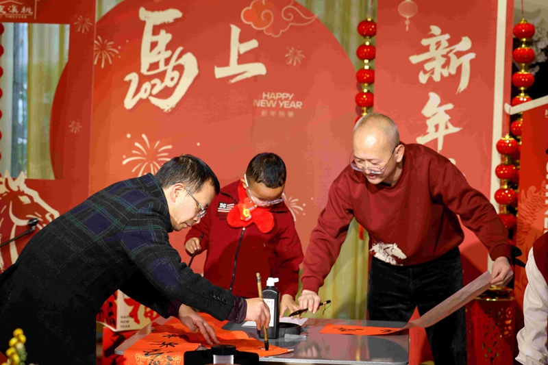 2月12日,家人在貴州省遵義市紅花崗區忠莊街道桃溪庭院家庭春晚上現場寫春聯。李仁軍攝