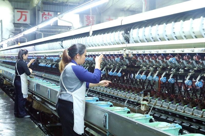 工人在荔波縣眾緣繭絲有限公司生產車間內的自動繅絲機上查看絲線 。.JPG