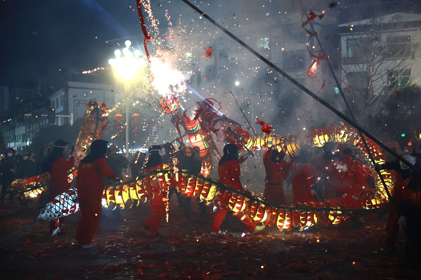 2月27日晚，貴州省黔東南苗族侗族自治州施秉縣城街頭，社區龍燈隊的漢子們在炸響的鞭炮火光下舞動“亮龍”。
