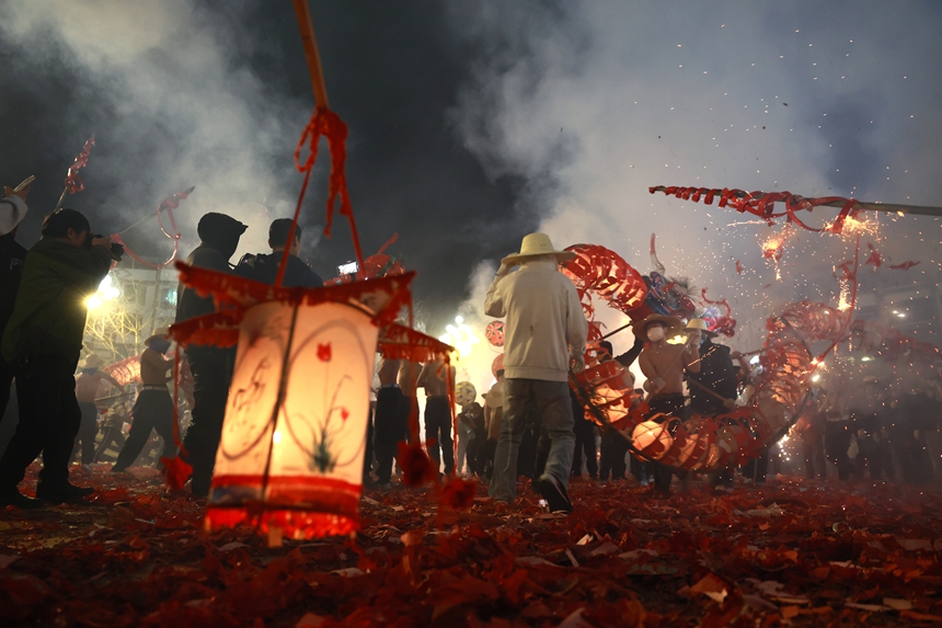 2月27日晚，貴州省黔東南苗族侗族自治州施秉縣城街頭，社區龍燈隊的漢子們在炸響的鞭炮火光下舞動“亮龍”。