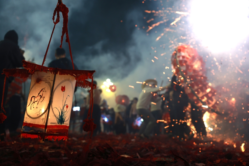 2月27日晚，貴州省黔東南苗族侗族自治州施秉縣城街頭，社區龍燈隊的漢子們在炸響的鞭炮火光下舞動“亮龍”。 