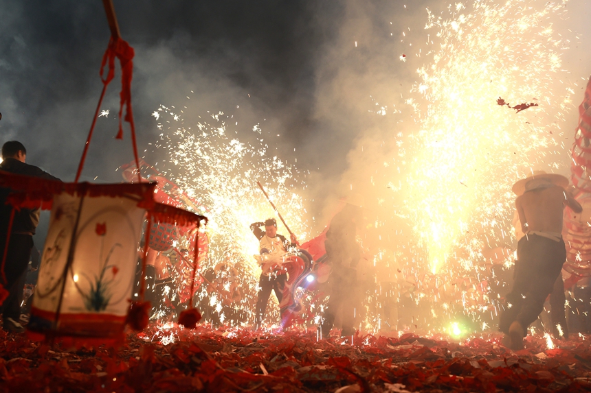2月27日晚，貴州省黔東南苗族侗族自治州施秉縣城街頭，社區龍燈隊的漢子們在炸響的鞭炮火光下舞動“亮龍”。