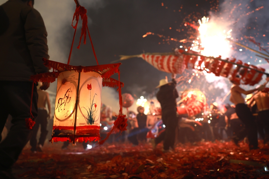 2月27日晚，貴州省黔東南苗族侗族自治州施秉縣城街頭，社區龍燈隊的漢子們在炸響的鞭炮火光下舞動“亮龍”。