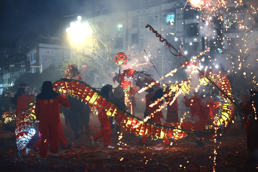 2月27日晚，貴州省黔東南苗族侗族自治州施秉縣城街頭，社區龍燈隊的漢子們在炸響的鞭炮火光下舞動“亮龍”。