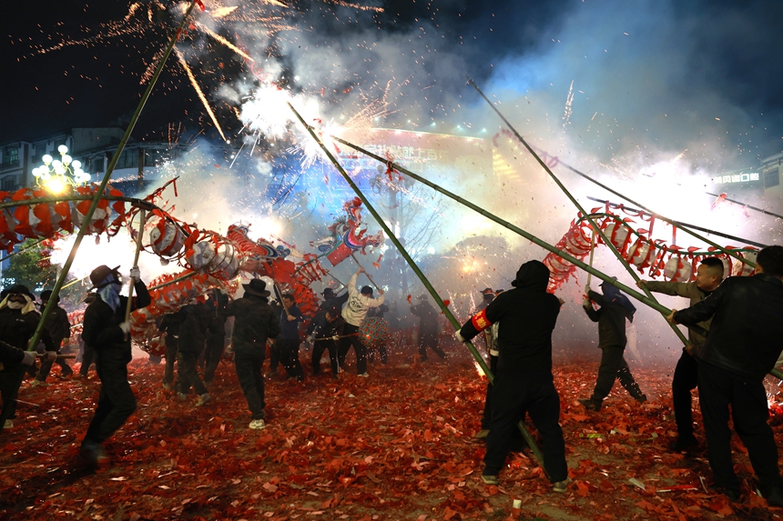 2月27日晚，貴州省黔東南苗族侗族自治州施秉縣城街頭，市民點燃捆綁在竹竿上的鞭炮伸向舞動的“亮龍”。