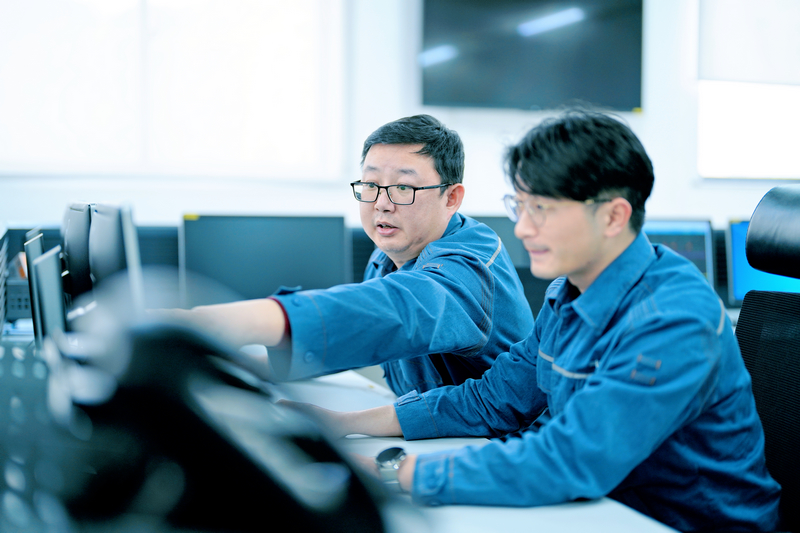 周敬余(左)給新員工講解監控信號的作用。陳濤攝