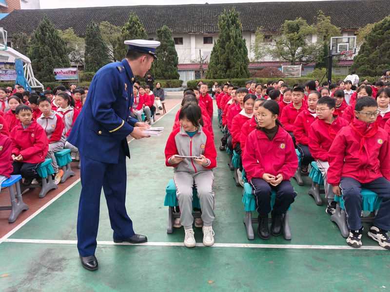 施秉縣消防宣傳員向施秉縣第二小學學生發放《中小學生消防安全知識讀本》。