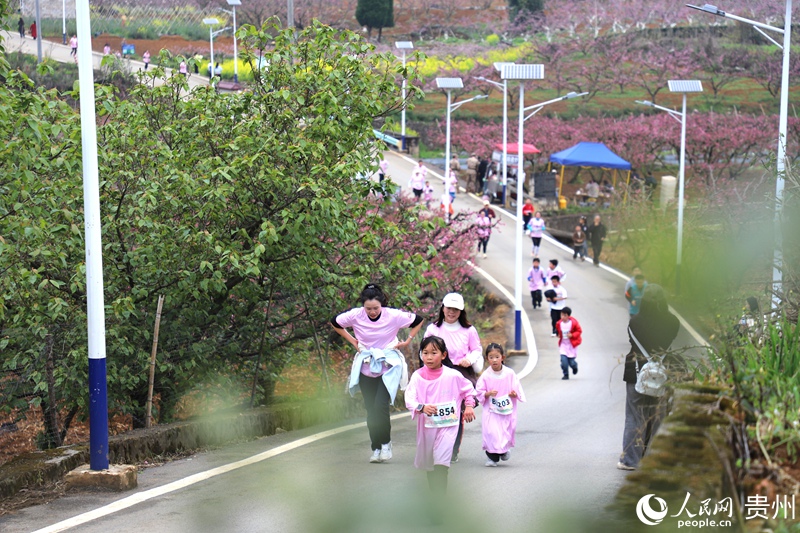 參賽選手與市民游客奔跑在桃花掩映的鄉村賽道。人民網 龍章榆 攝