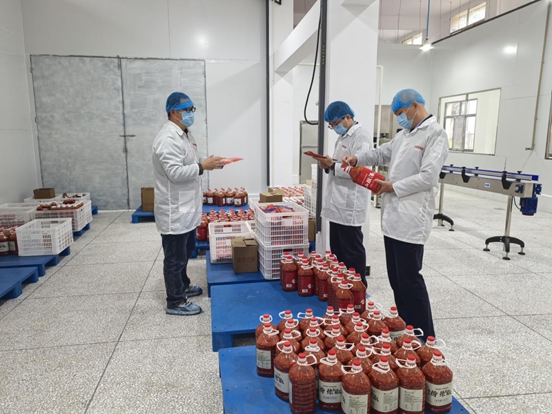 (圖五 稅務干部了解魚醬酸制作工藝和成品并宣講數電票提額規范流程)