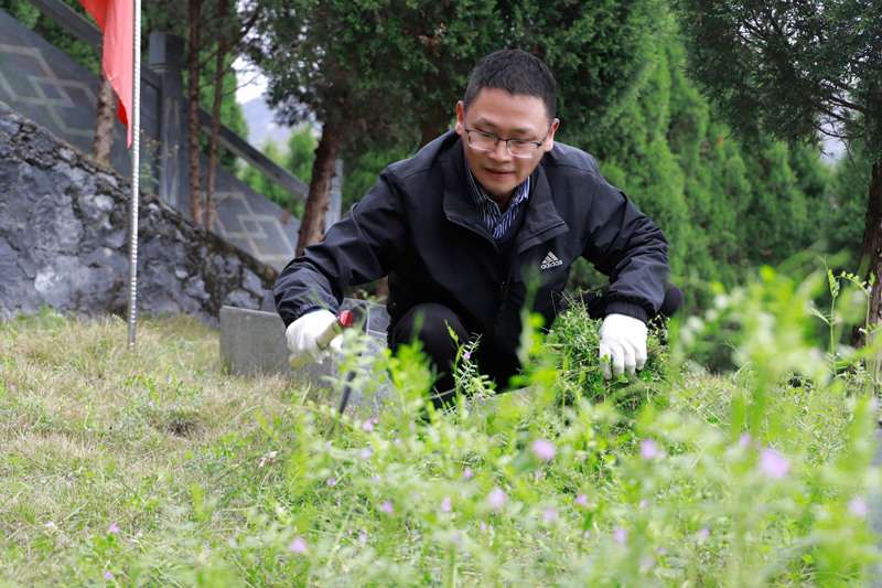 志愿者在用鐮刀除草。