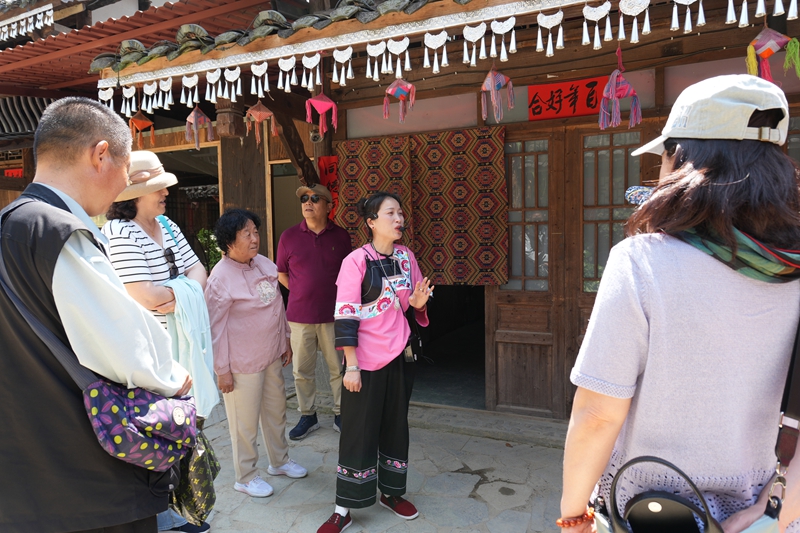景區講解員給游客講解民俗及風景。