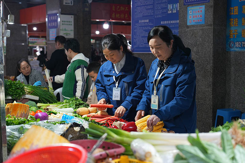 農(nóng)貿(mào)市場(chǎng)工作人員對(duì)蔬菜進(jìn)行抽查。