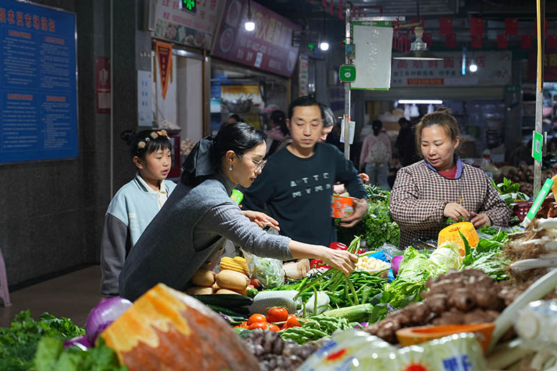 市民們?cè)谵r(nóng)貿(mào)市場(chǎng)挑選春菜。
